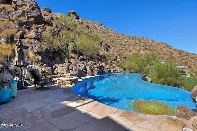 view of pool with a mountain view, a patio, and an outdoor fire pit