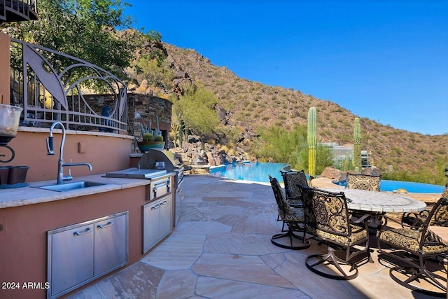 view of patio / terrace featuring a mountain view, area for grilling, sink, and a grill