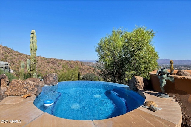 view of swimming pool with a mountain view and a jacuzzi