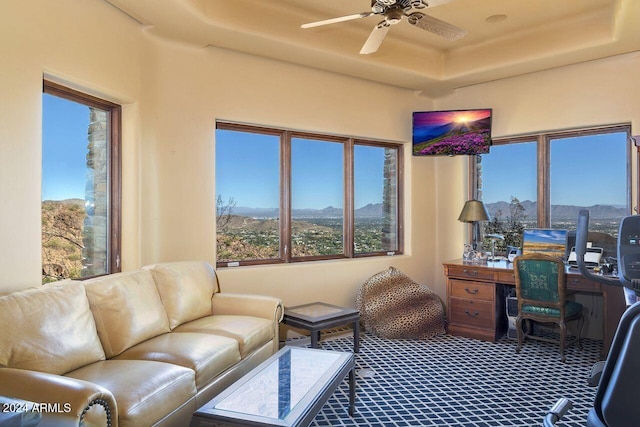 office area with carpet flooring, ceiling fan, and a raised ceiling