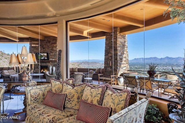 living room featuring beam ceiling, a stone fireplace, and a mountain view