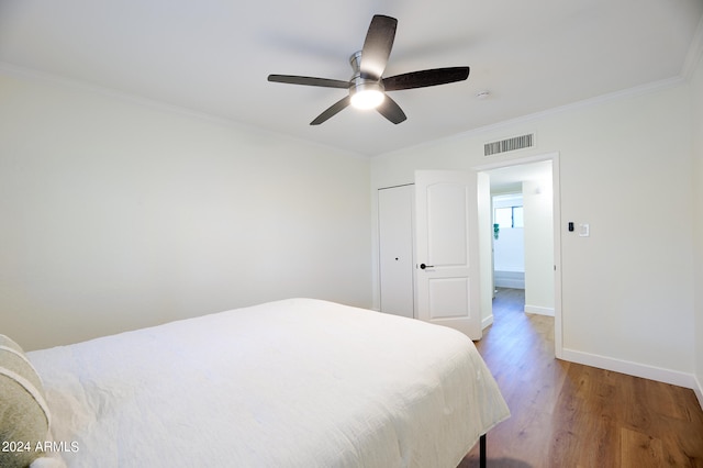 bedroom featuring ceiling fan, wood-type flooring, crown molding, and a closet