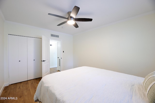 bedroom featuring ceiling fan, a closet, light hardwood / wood-style flooring, and crown molding