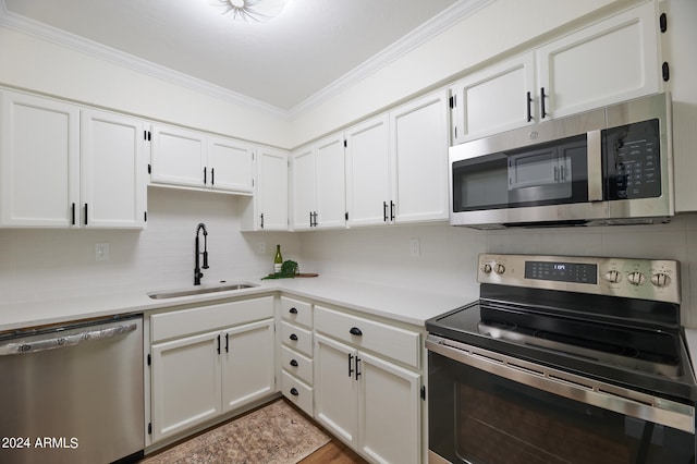 kitchen with white cabinetry, stainless steel appliances, sink, backsplash, and ornamental molding