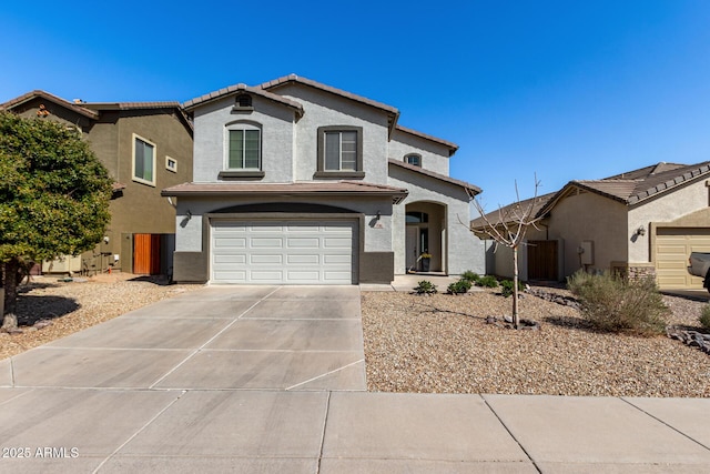 mediterranean / spanish home with a tile roof, stucco siding, concrete driveway, and a garage