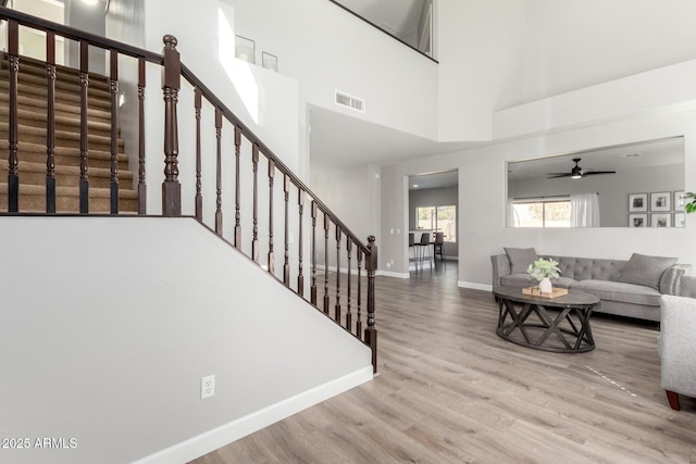 living room with visible vents, baseboards, stairway, a high ceiling, and wood finished floors