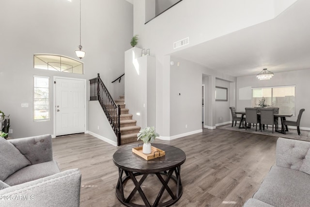 living room with a wealth of natural light, visible vents, wood finished floors, and stairs