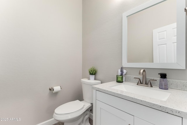 half bathroom with toilet, vanity, and baseboards