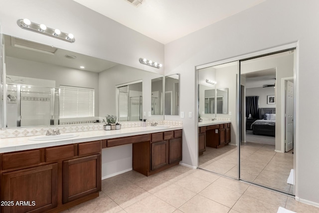 bathroom featuring tile patterned floors, a sink, a stall shower, and double vanity