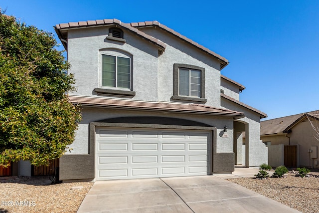 traditional home featuring stucco siding, concrete driveway, an attached garage, and a tile roof