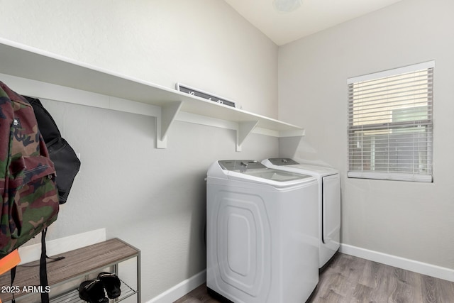 laundry area with baseboards, separate washer and dryer, wood finished floors, and laundry area