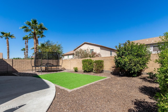 view of yard featuring a patio, a trampoline, and a fenced backyard