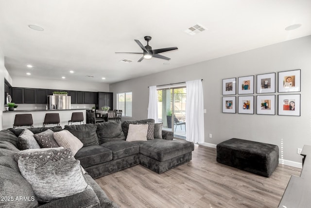 living area with light wood finished floors, visible vents, and baseboards