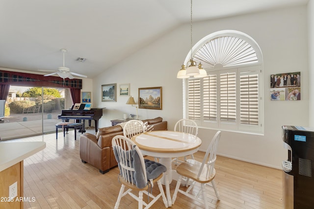 dining area with ceiling fan, high vaulted ceiling, and light wood-type flooring