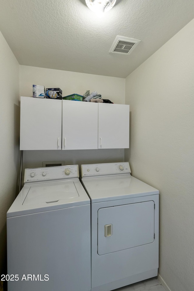 washroom featuring independent washer and dryer, cabinets, and a textured ceiling