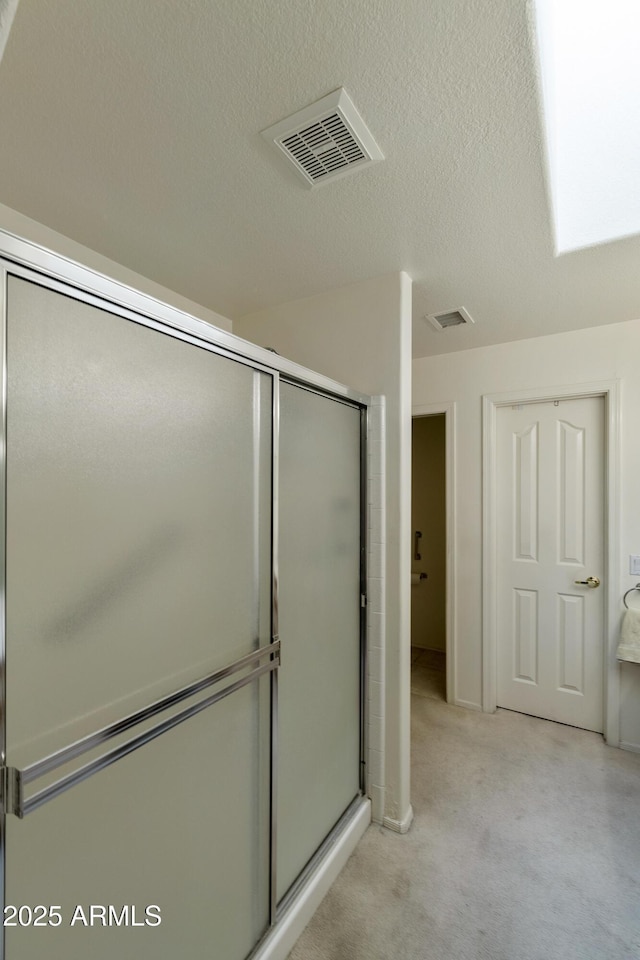 bathroom with a shower with shower door and a textured ceiling