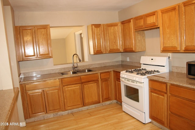 kitchen featuring sink, white gas stove, and light hardwood / wood-style flooring