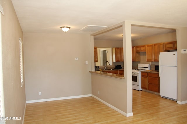 kitchen with white appliances, sink, and light hardwood / wood-style flooring