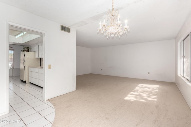 spare room featuring an inviting chandelier and light carpet