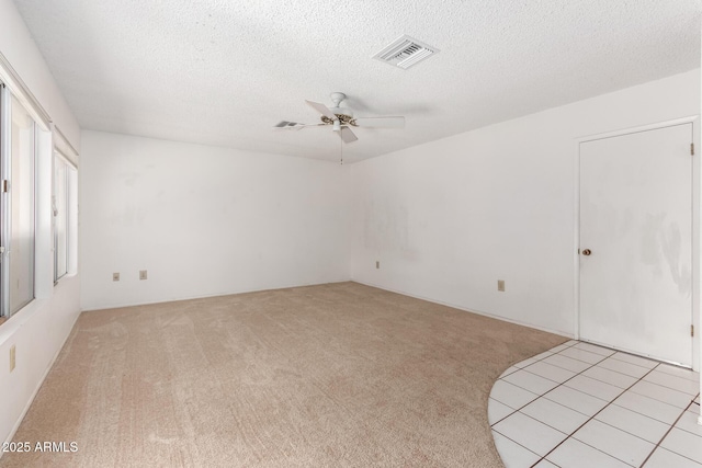 carpeted spare room featuring ceiling fan and a textured ceiling