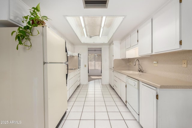 kitchen with sink, white appliances, light tile patterned floors, tasteful backsplash, and white cabinets