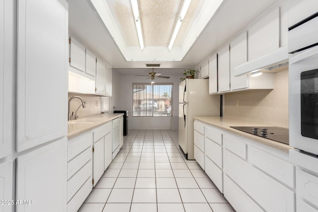 kitchen featuring white cabinetry, sink, a raised ceiling, and light tile patterned flooring