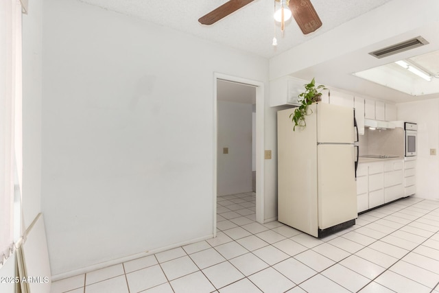 interior space featuring ceiling fan, white appliances, light tile patterned floors, and white cabinets