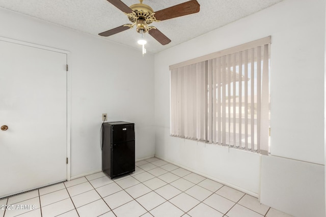 tiled empty room featuring ceiling fan and a textured ceiling