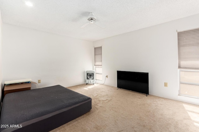 unfurnished bedroom featuring heating unit, ceiling fan, carpet floors, and a textured ceiling