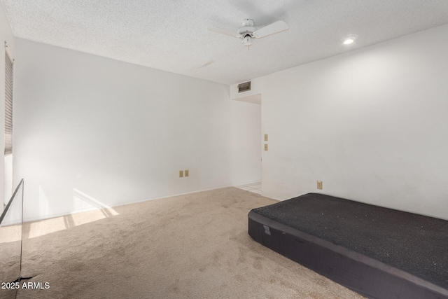 unfurnished bedroom with ceiling fan, light carpet, and a textured ceiling