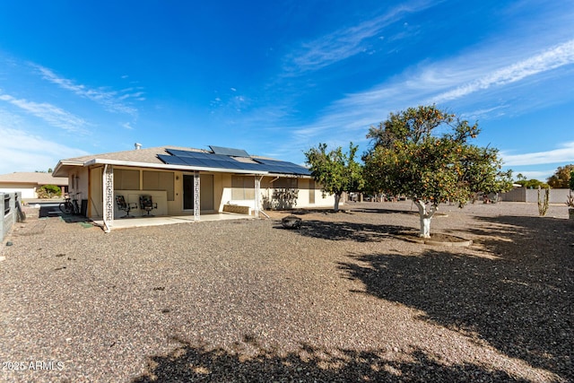 rear view of property featuring a patio area and solar panels