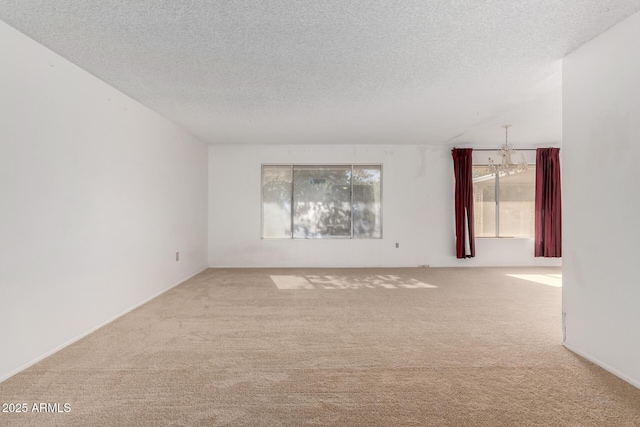 empty room featuring an inviting chandelier, carpet floors, and a textured ceiling