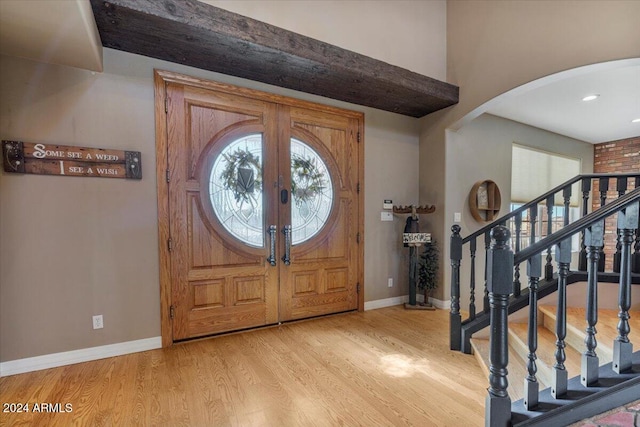 foyer featuring light hardwood / wood-style floors, beamed ceiling, and french doors