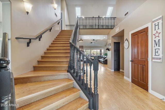 stairs featuring high vaulted ceiling, a skylight, and hardwood / wood-style floors