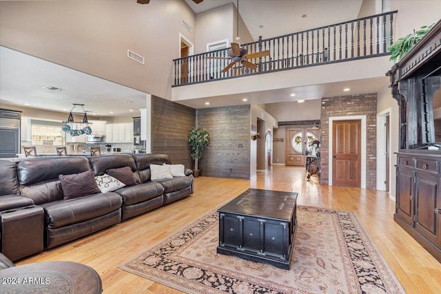 living room featuring a towering ceiling, ceiling fan, and light hardwood / wood-style floors