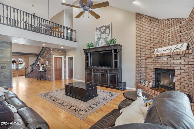 living room with hardwood / wood-style floors, ceiling fan, high vaulted ceiling, and a brick fireplace