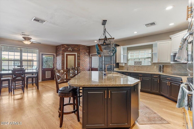 kitchen featuring a kitchen island, white cabinetry, light wood-type flooring, pendant lighting, and ceiling fan