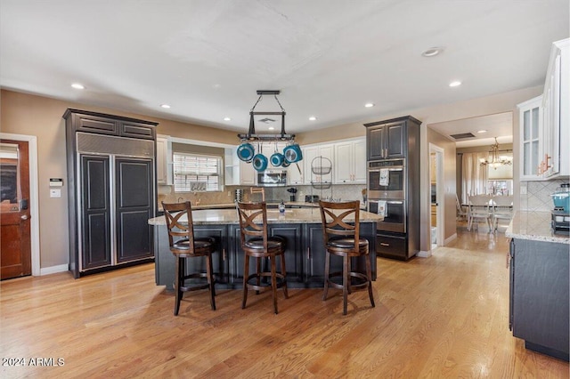 kitchen with stainless steel appliances, light hardwood / wood-style floors, a breakfast bar area, a kitchen island, and decorative backsplash