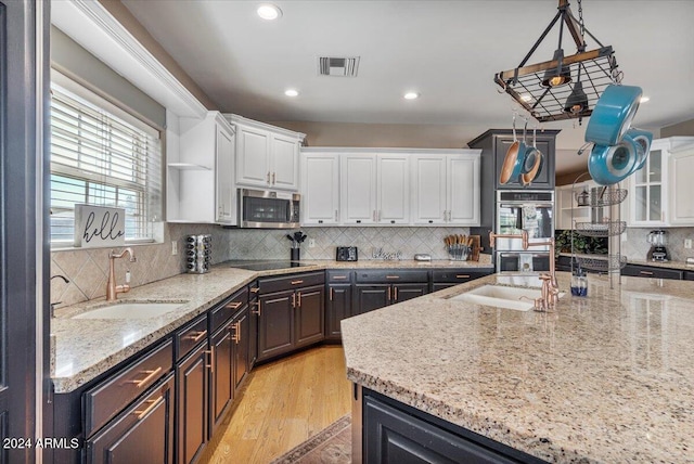 kitchen with light hardwood / wood-style floors, white cabinets, sink, backsplash, and appliances with stainless steel finishes