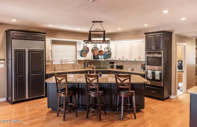 kitchen featuring light wood-type flooring, appliances with stainless steel finishes, a breakfast bar area, and a kitchen island with sink