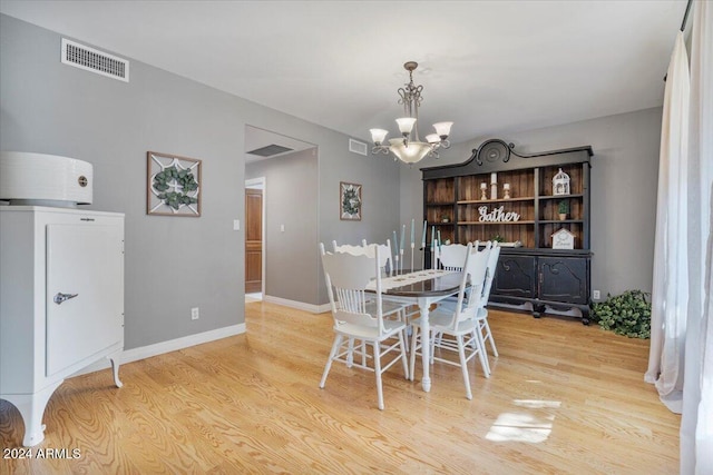 dining space with light wood-type flooring and an inviting chandelier