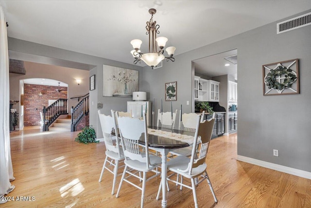 dining area with light hardwood / wood-style floors and a chandelier