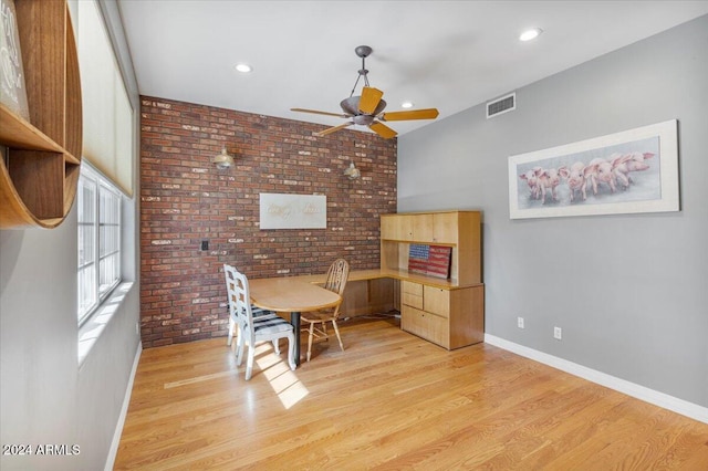 dining area with ceiling fan, light hardwood / wood-style floors, and brick wall