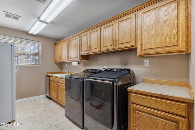 laundry area with separate washer and dryer, cabinets, light wood-type flooring, and sink