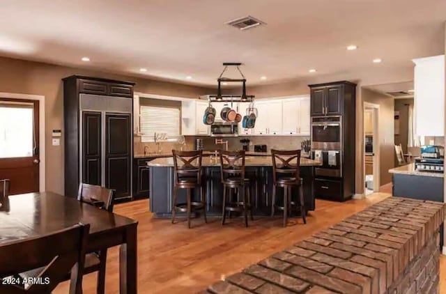 kitchen with a kitchen bar, appliances with stainless steel finishes, light hardwood / wood-style floors, and a kitchen island