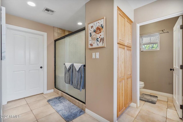 bathroom featuring walk in shower, tile patterned flooring, and toilet