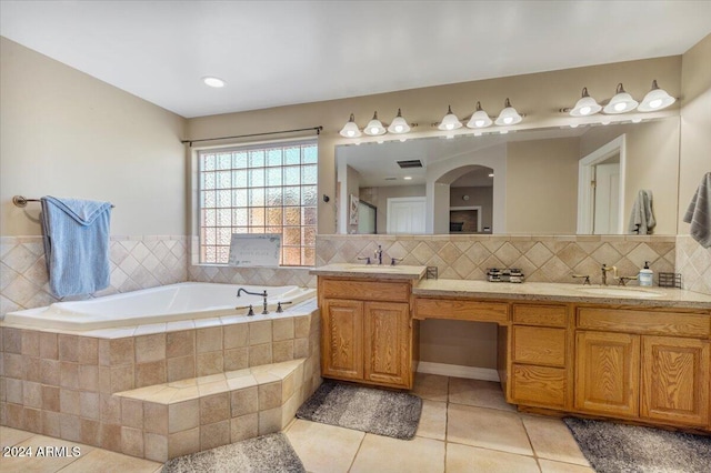 bathroom featuring vanity, decorative backsplash, tile patterned flooring, and a relaxing tiled tub