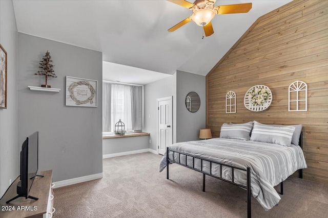 carpeted bedroom featuring wood walls, ceiling fan, and vaulted ceiling