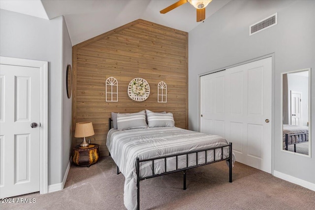 bedroom with a closet, carpet flooring, high vaulted ceiling, wooden walls, and ceiling fan