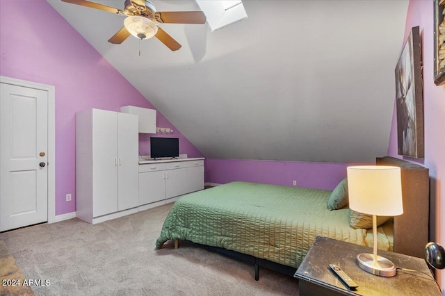 bedroom featuring light carpet, ceiling fan, and vaulted ceiling with skylight